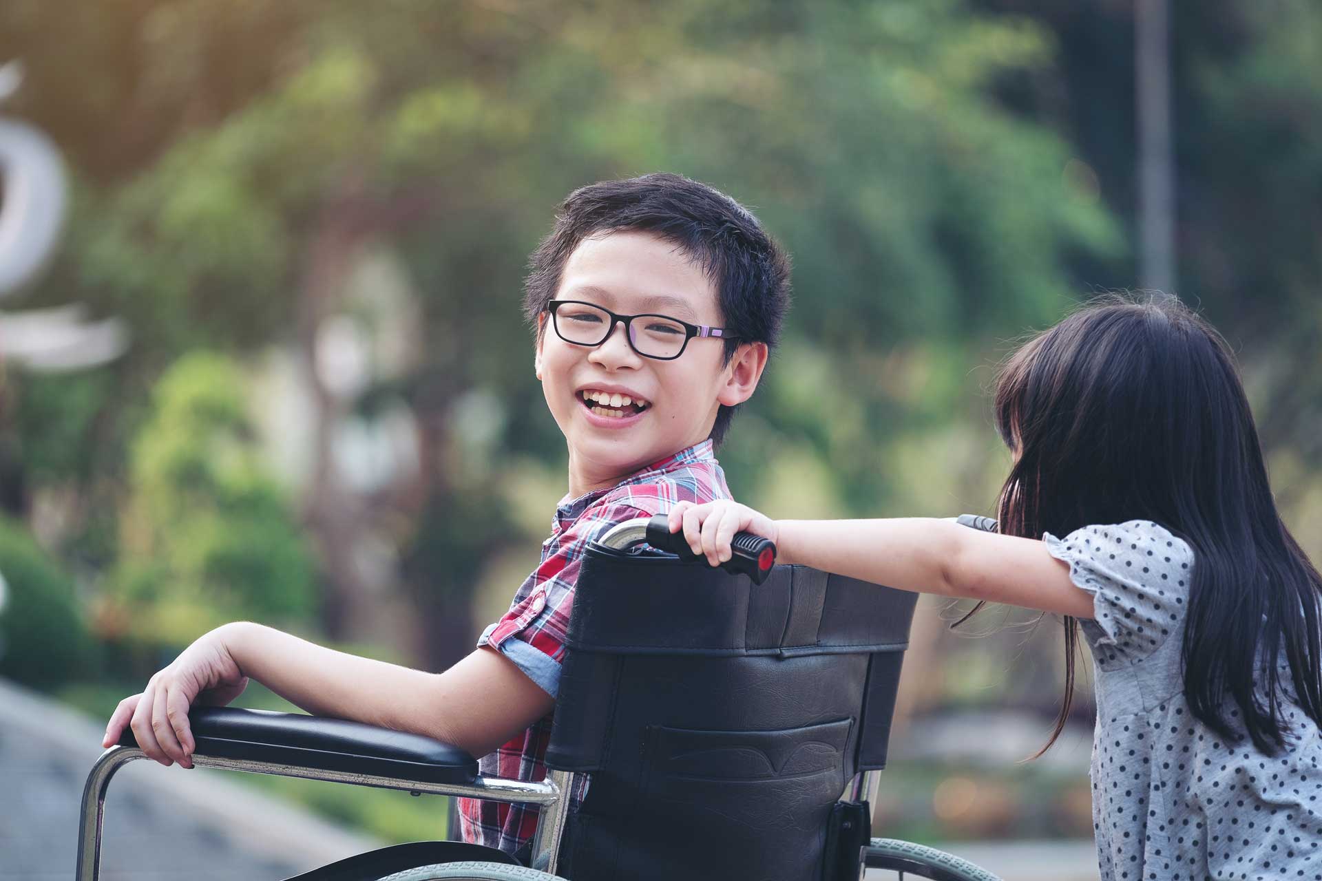 boy in wheelchair being pushed by sister